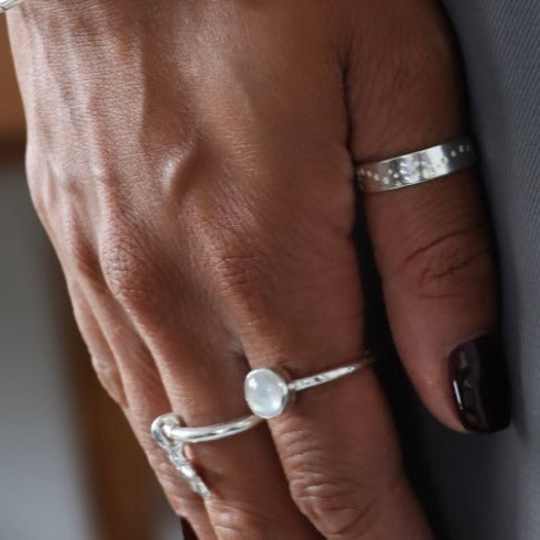 A close-up image of a person's hand showcasing a Starry Night ring on their finger, with the ring's embossed stars visible. The background suggests a home environment.