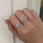 Hand wearing two silver rings with a light-colored background