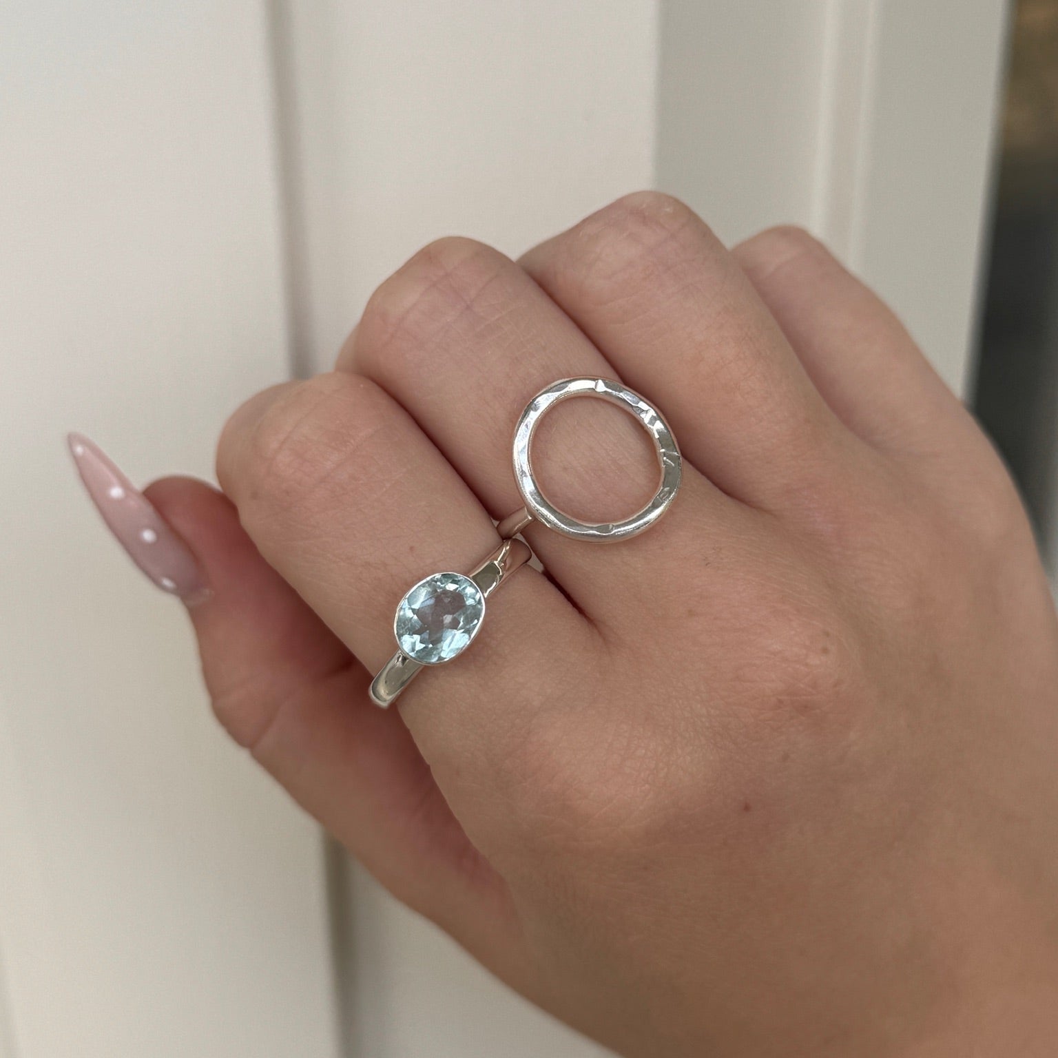 Hand wearing two silver rings with a light-colored background