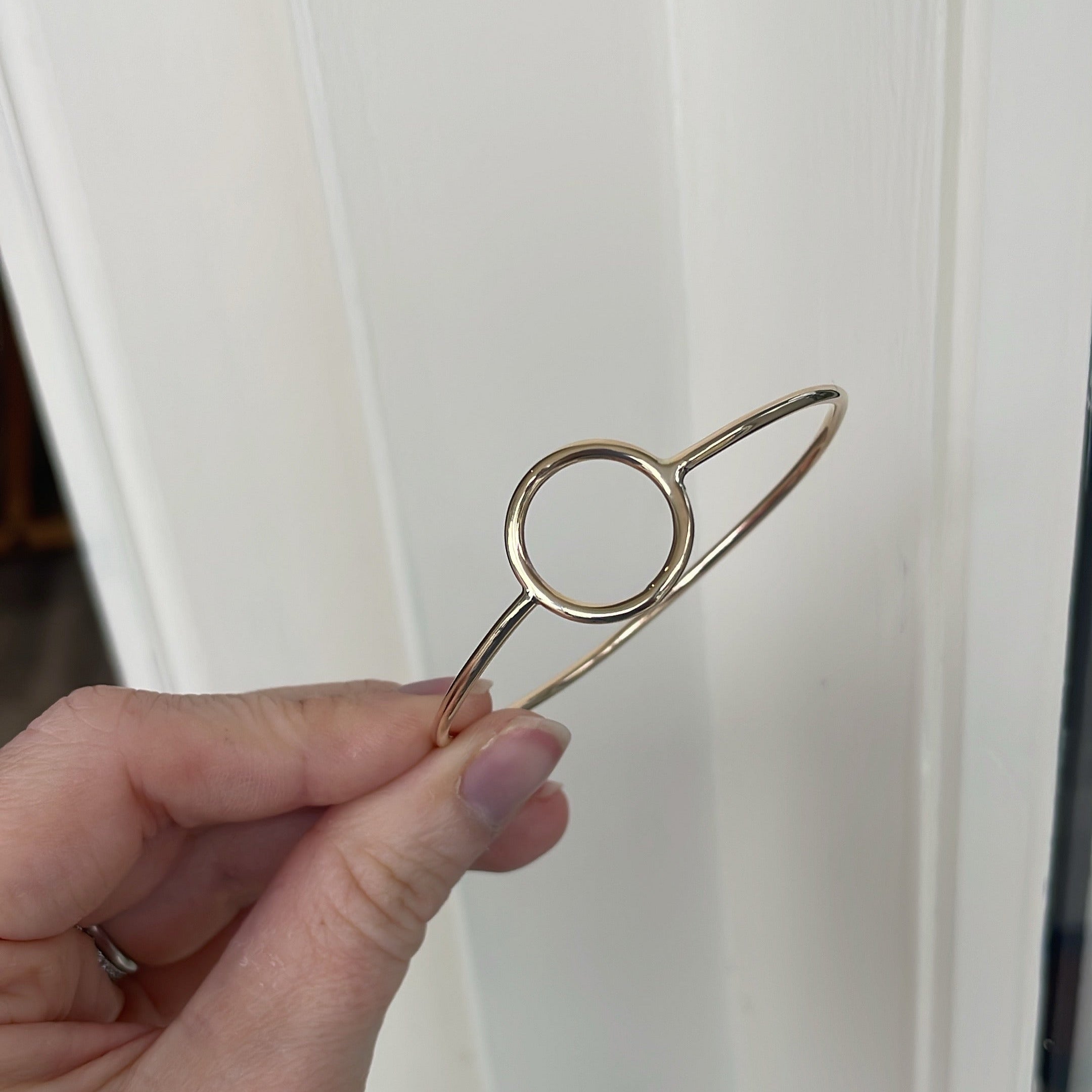 Hand holding a small metallic clip against a white curtain background
