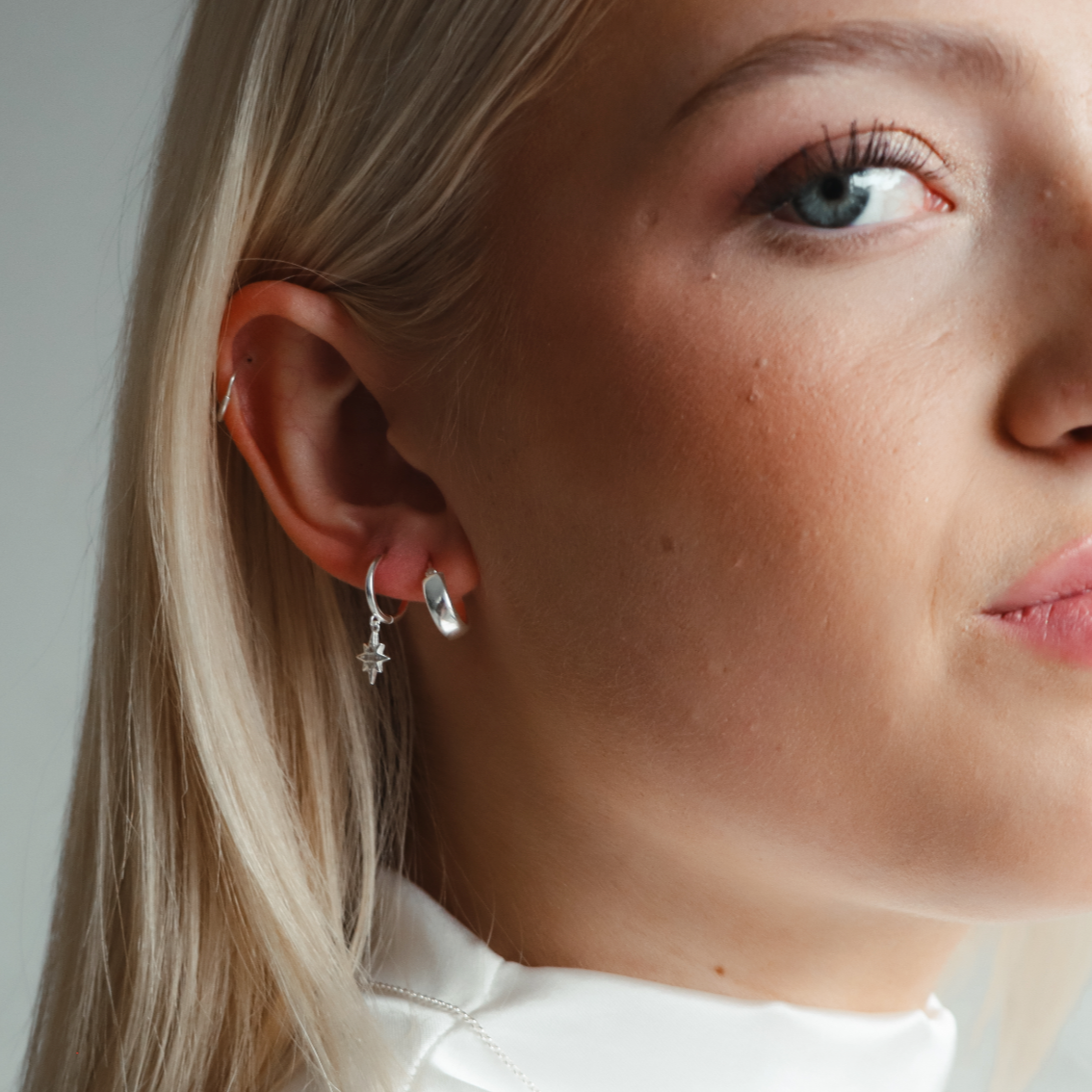 A woman wearing medium-sized silver hoop earrings with a bold curve design.