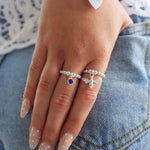 Hand wearing two silver rings with gemstones on a denim background