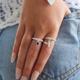 Hand wearing two silver rings with gemstones on a denim background